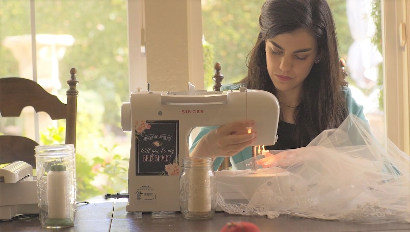 hand sewing bespoke bridal veils at the sewing machine as designer stitches the tulle and French lace