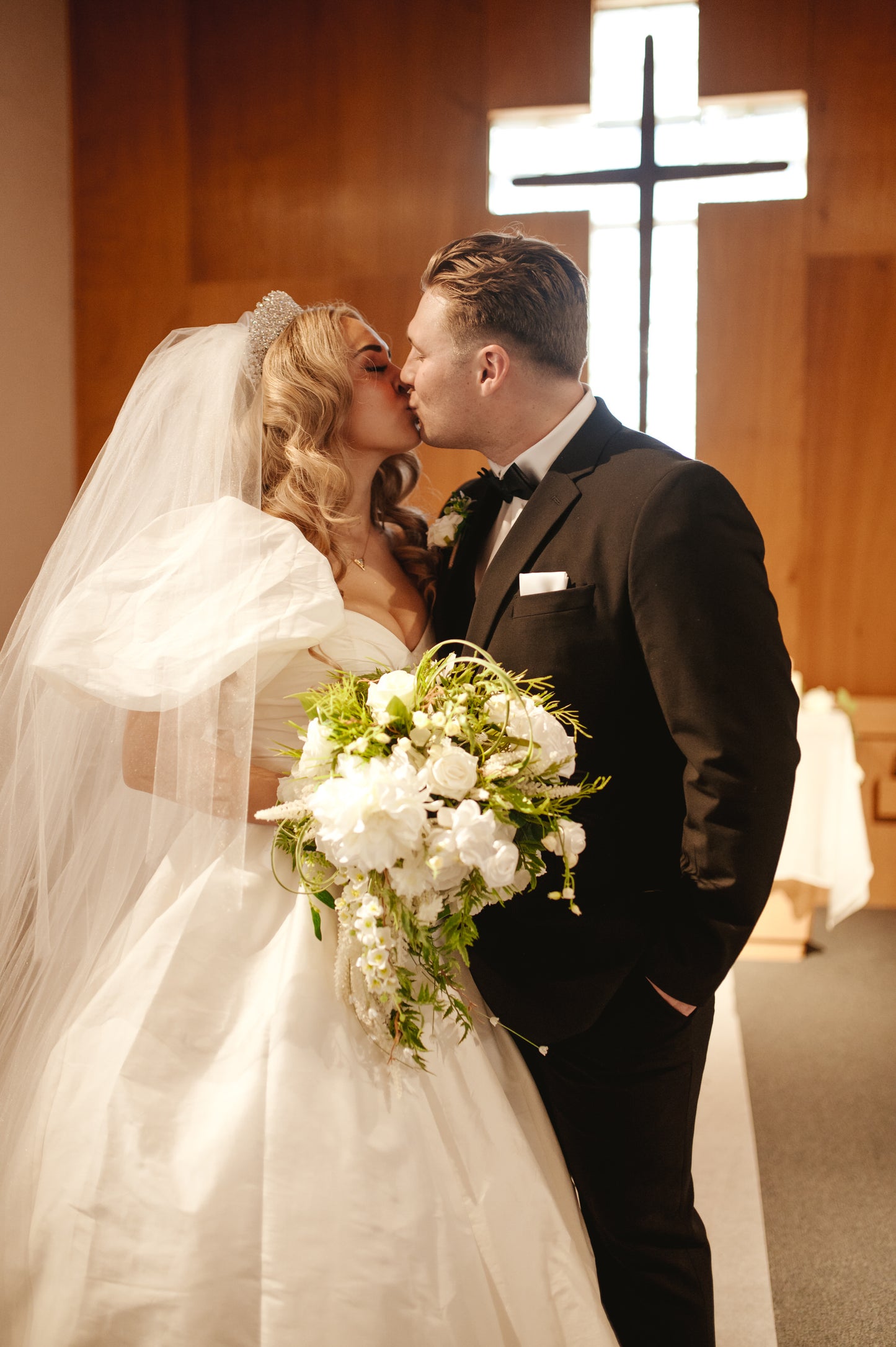 christian Couple kissing in front of a cross and bride wearing a diy bridal sleeve set with princess inspired gown