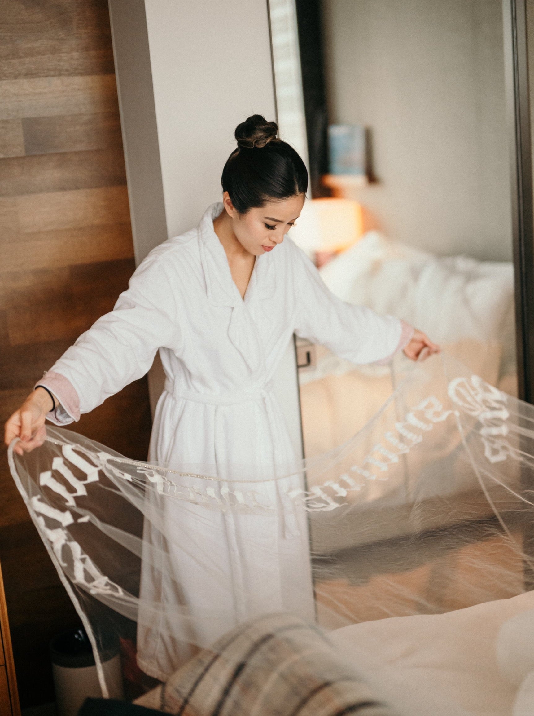 bride holding long bespoke bridal veil with embroidered phrase on bottom