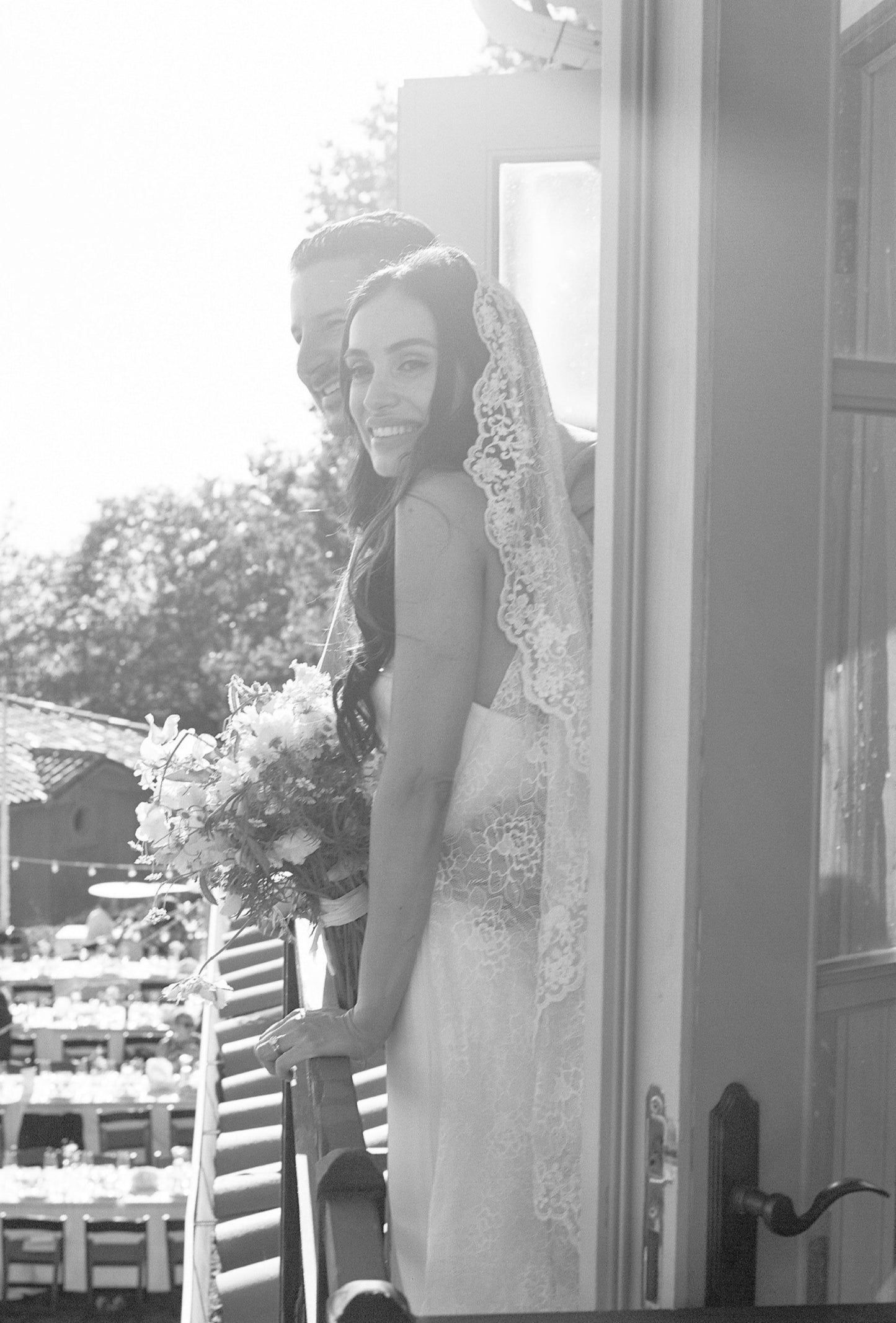 elegant traditional fingertip length mantilla with allover lace as bride and groom look out balcony