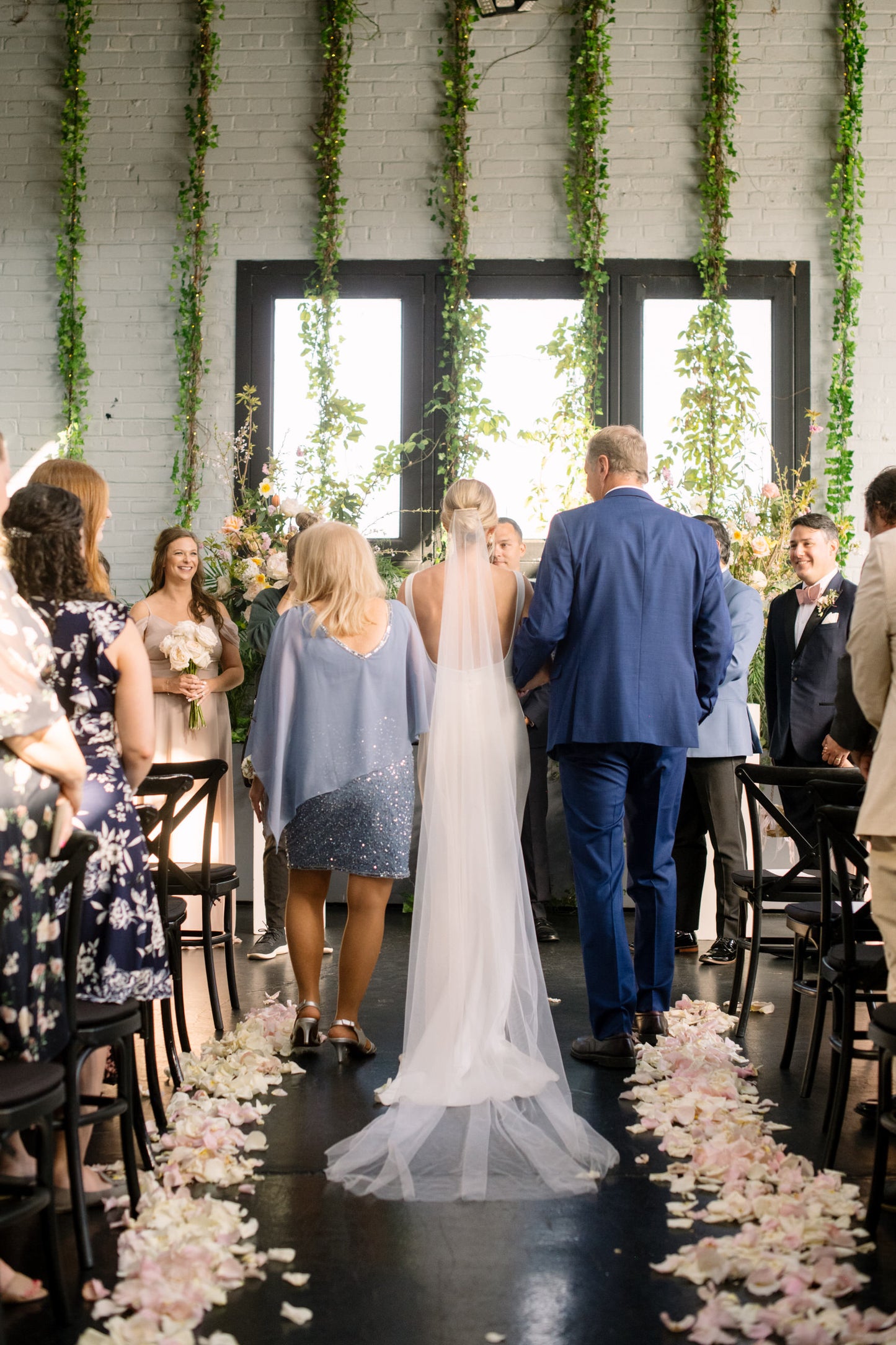bride walking down the aisle in soft silk cathedral wedding veil with mom and dad on either side