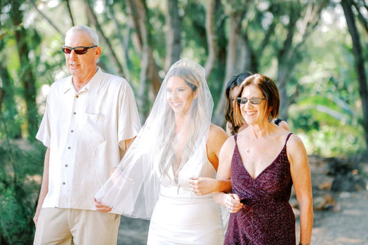 bride in blusher and crown walking down aisle