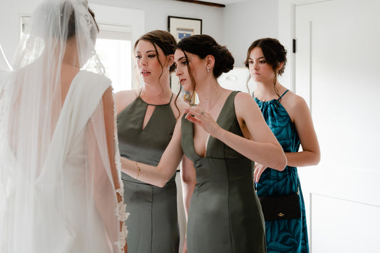 bride in lace chapel length bridal veil as bridesmaids in blue and green dresses help her get ready