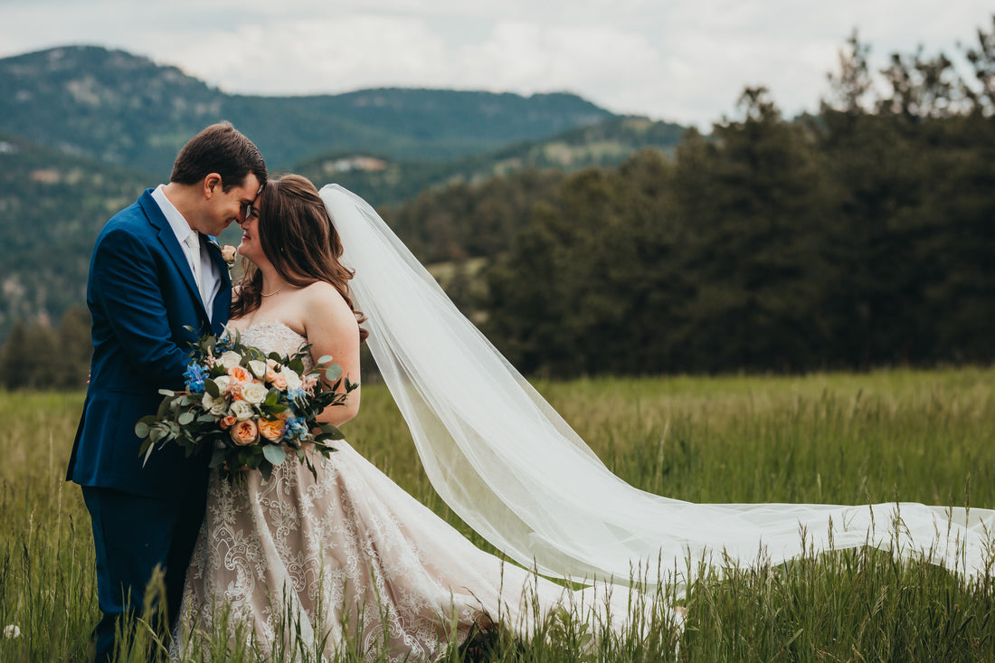 bride and groom embracing in the mountains with bride in long blush cathedral lace veil