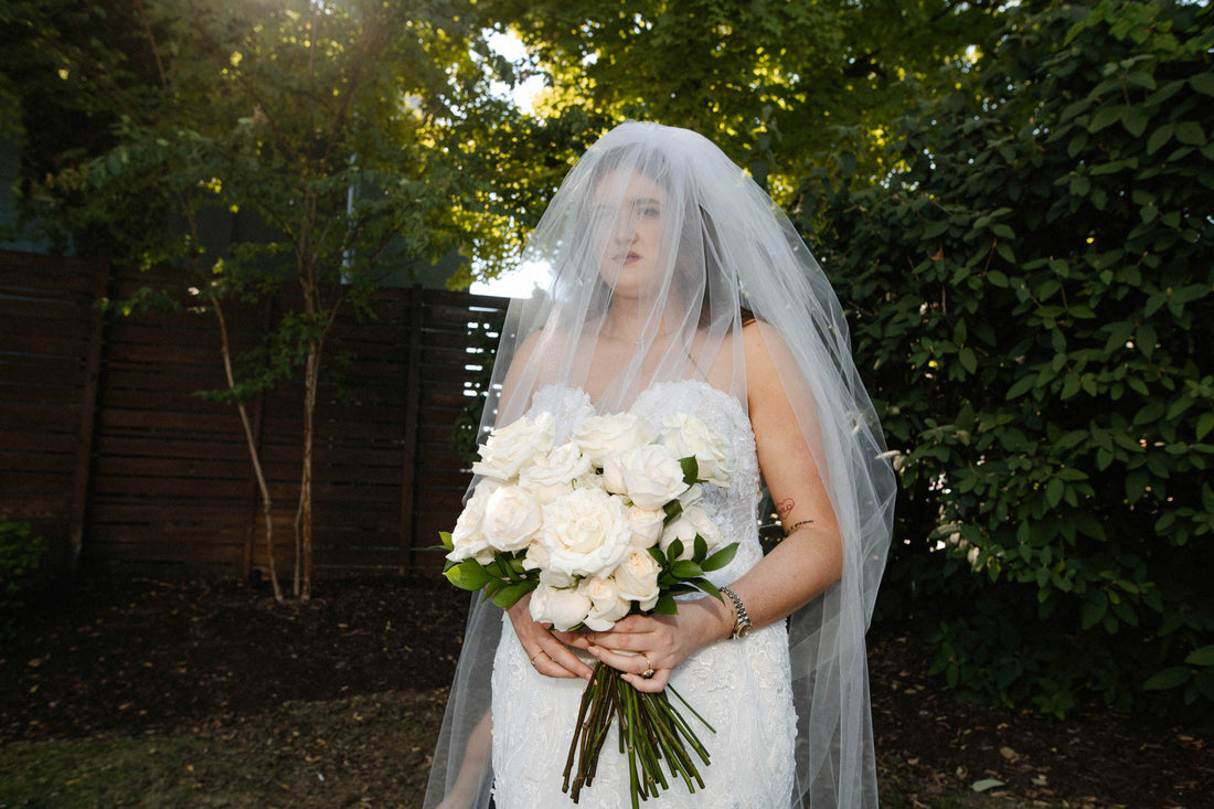 bride wearing a two layer blusher wedding veil over face in off white with white and cream bouquet