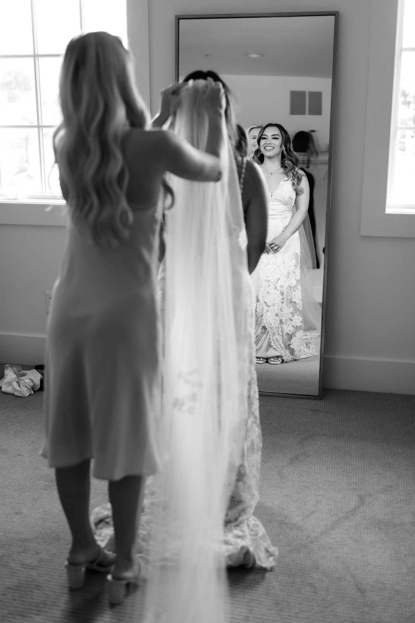 bridesmaid helping bride put on long cathedral veil with embroidered phrase