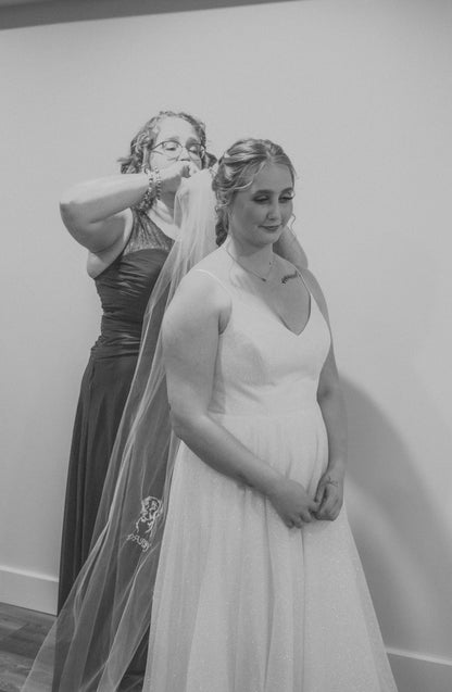 mom helping daughter get dressed for wedding wearing long bridal veil with lab dog portrait