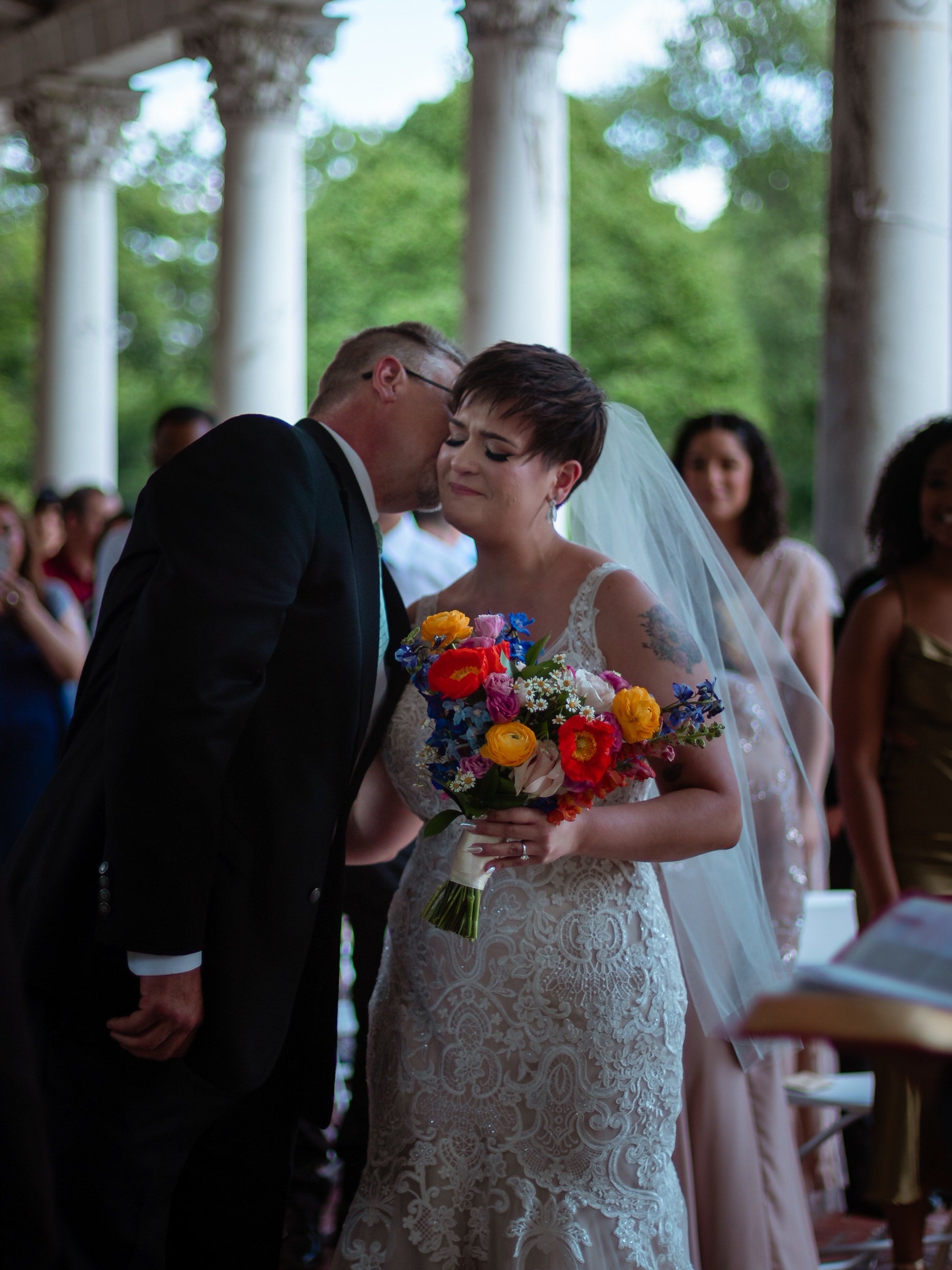 mid length ivory bridal veil in bride's short hair as she hold colorful wildflower bouquet