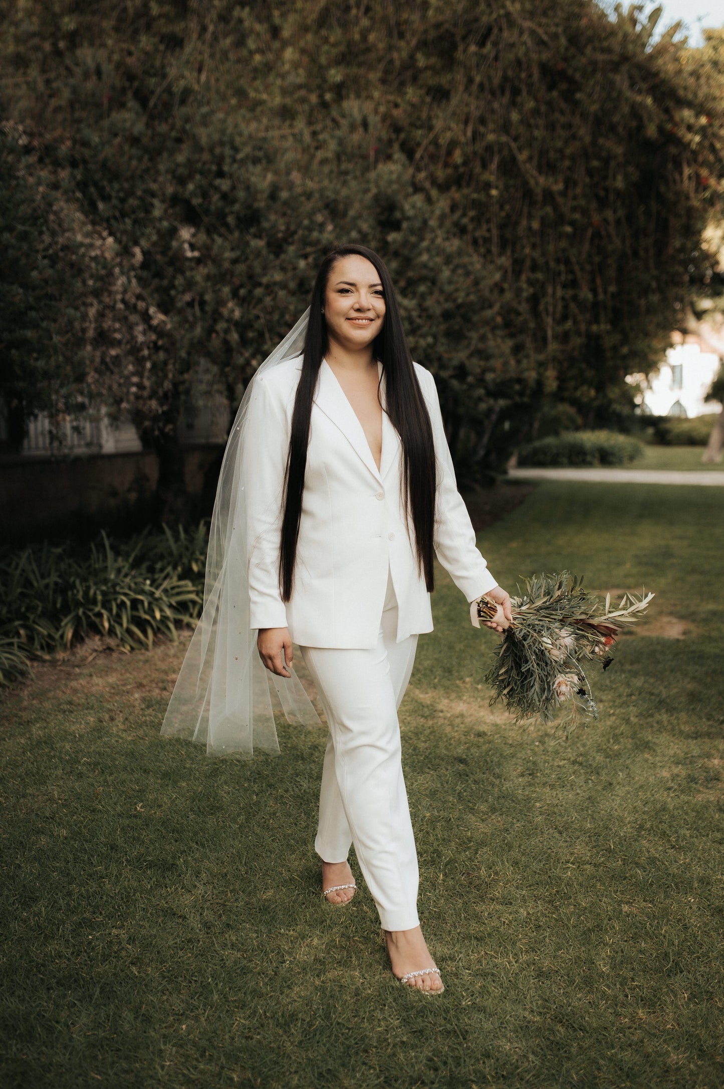 bride's white suit and knee length rhinestone wedding veil in long hair