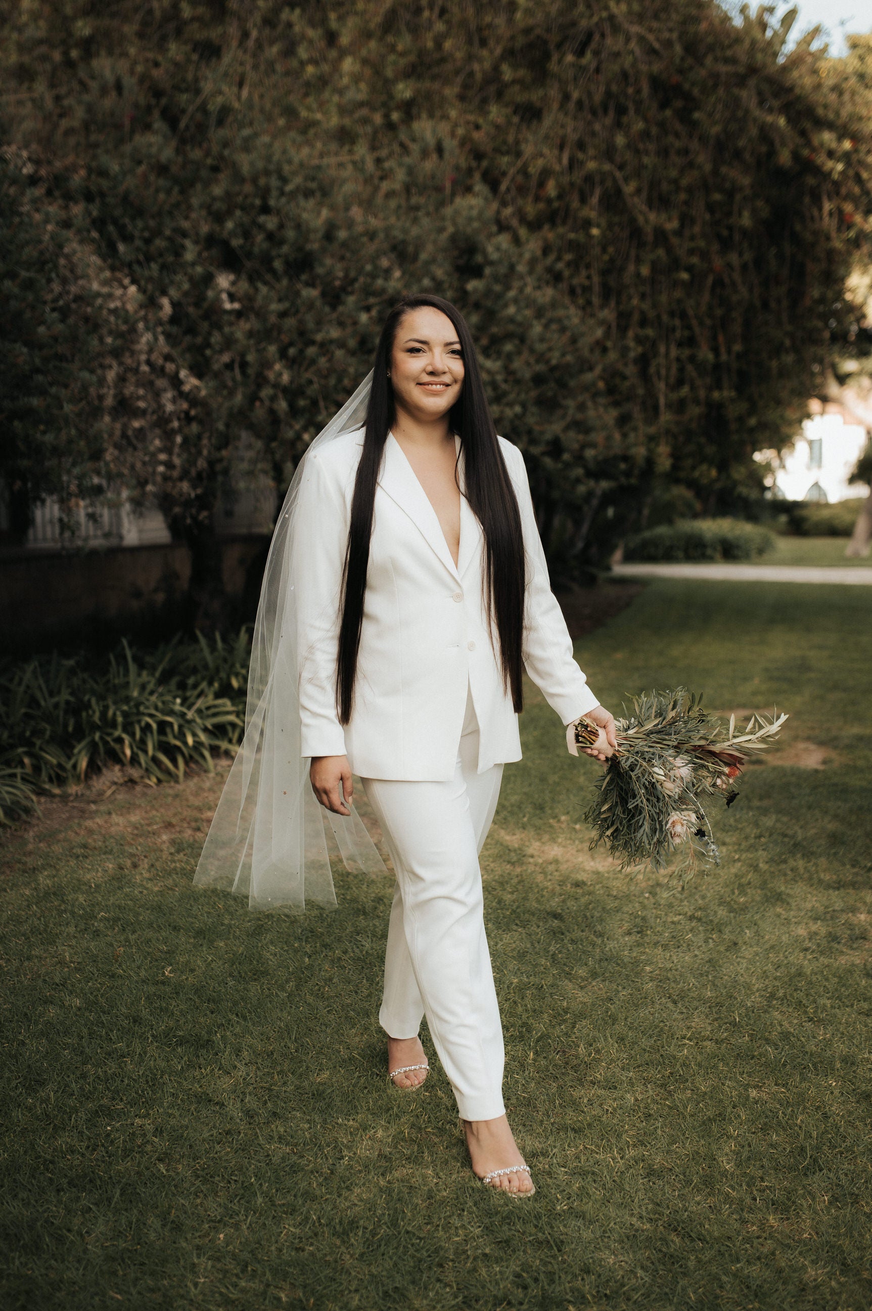 bride's white suit and knee length rhinestone wedding veil in long hair