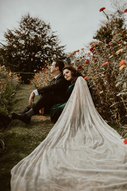 gold bridal cape draped for couple's engagement shoot with bride in green velvet gown