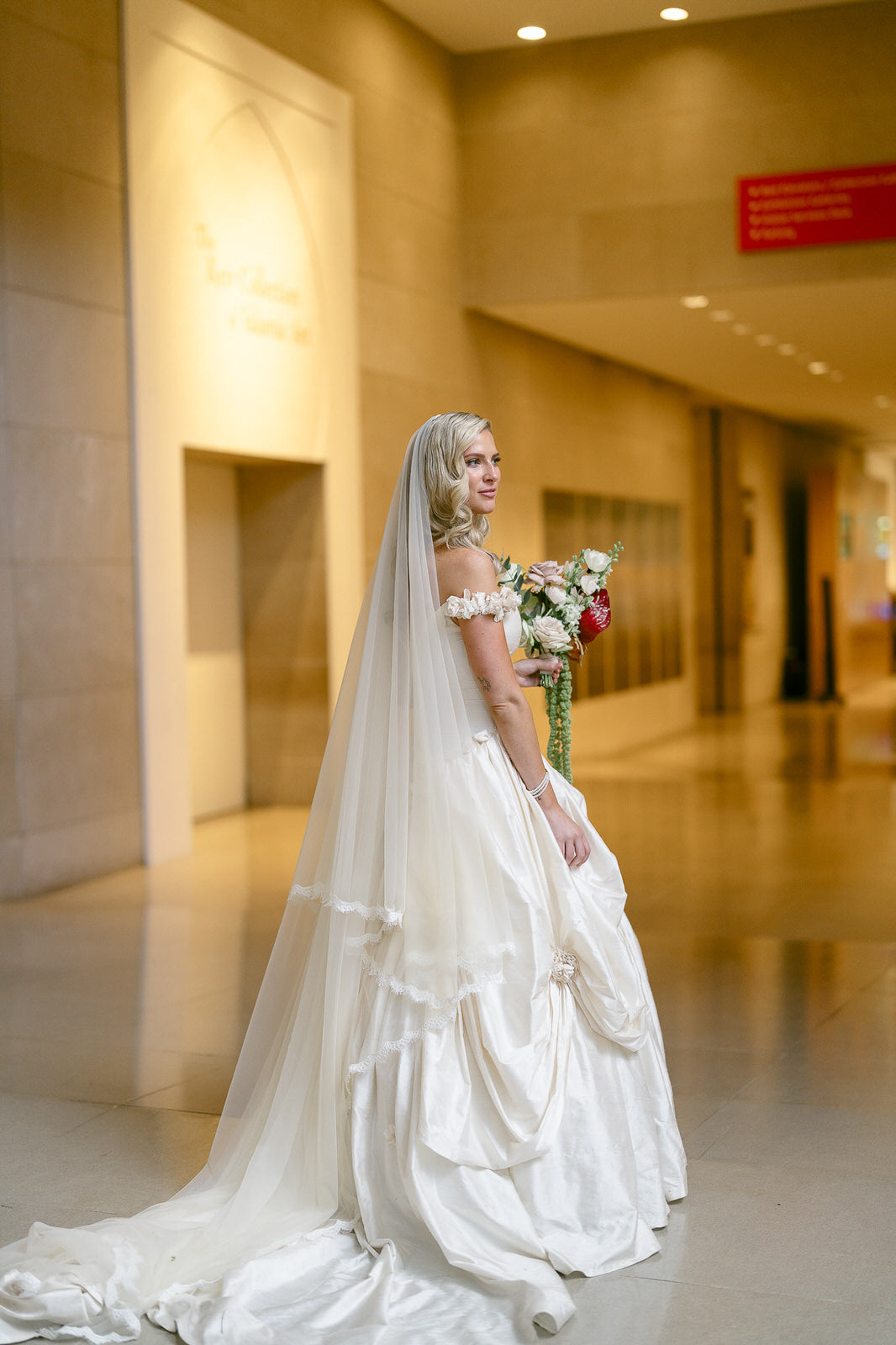 Bride in a tiered wedding dress wearing drop royal length cascade bridal veil made from vintage materials