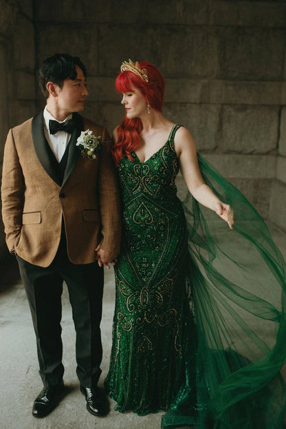 Bride and groom holding hands, redhead bride in a green dress with a long tulle  cape veil that she sewed herself
