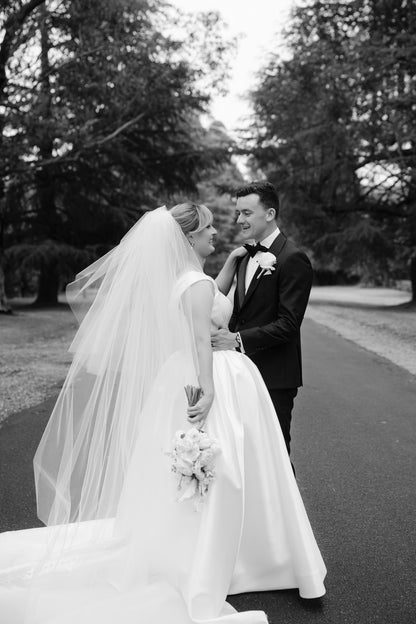 Black and white photo of a bride and groom with bride in classic ballgown and two layer blusher royal length wedding veil