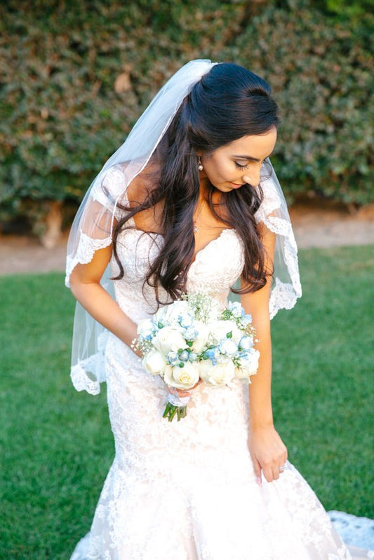 elegant bride with lace fingertip length wedding veil in half up hairstyle