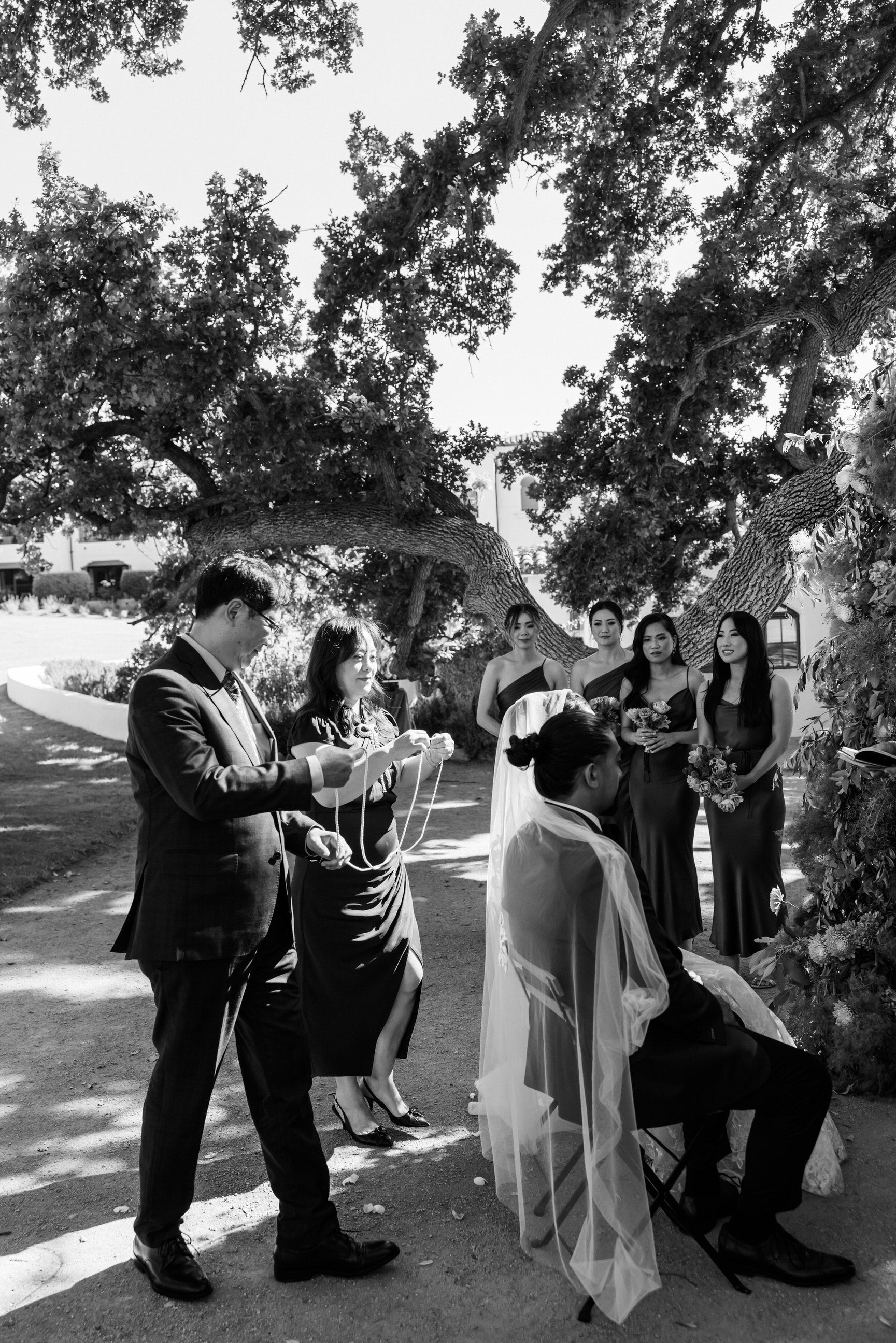 outdoor wedding with unity ceremony and mother of bride placing cords over couples shoulders