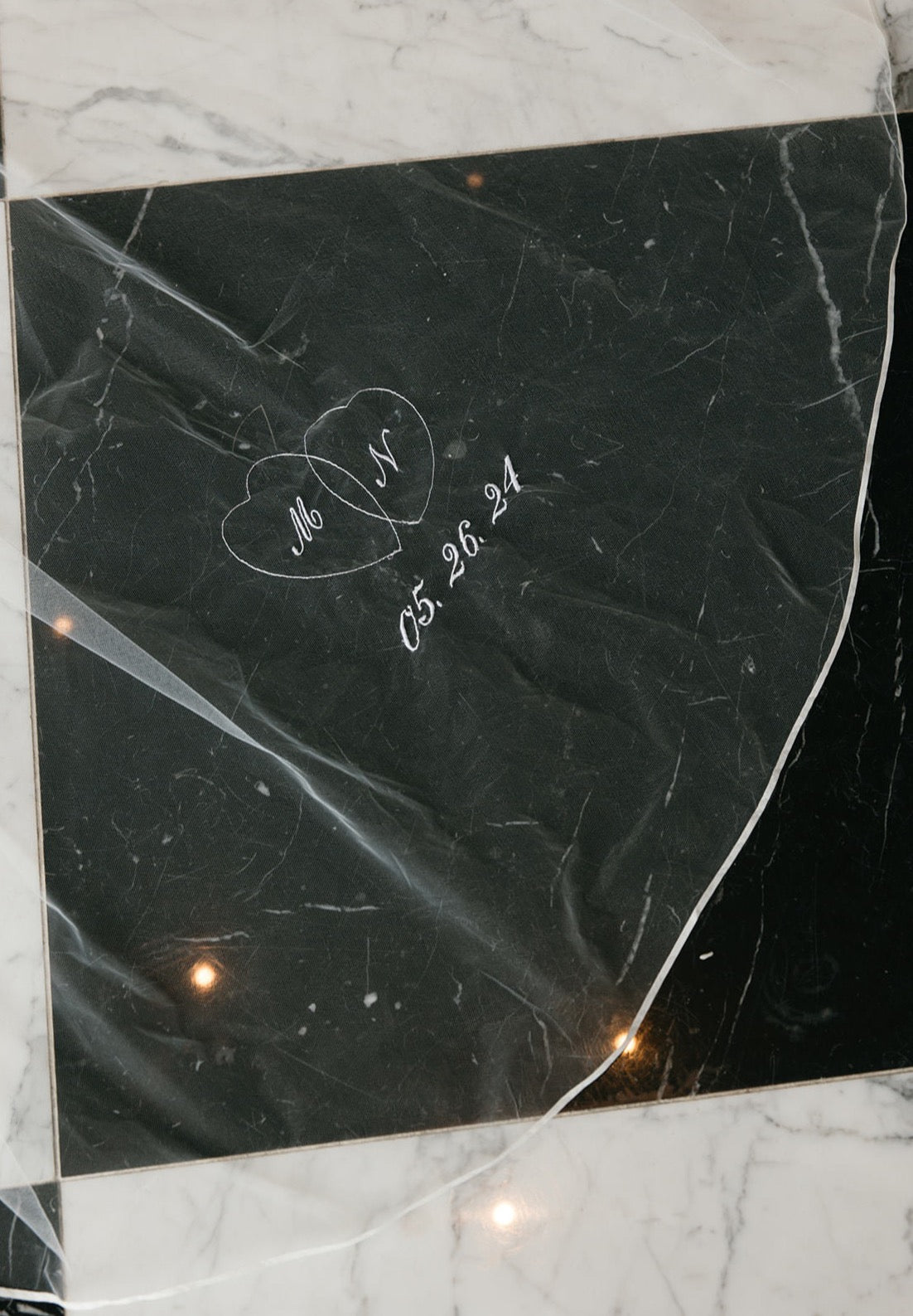 embroidered locked hearts in white thread stitching with couples initials on ribbon edged veil