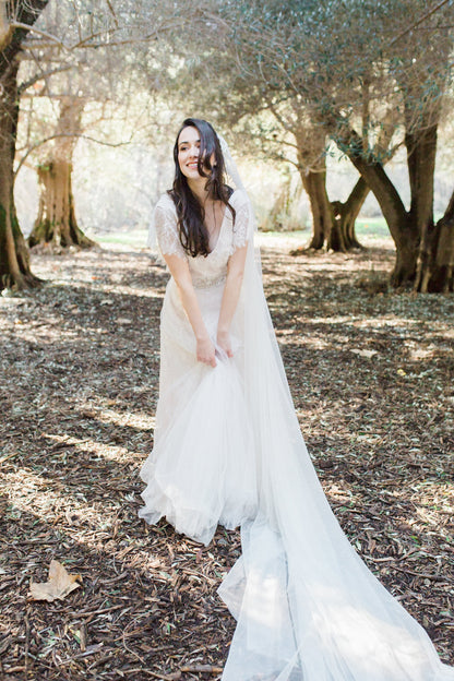 playful bride wearing long chapel length off white wedding veil with cap style veil
