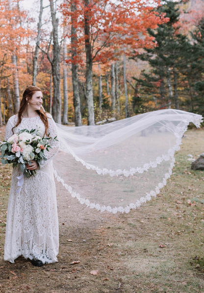 vintage boho bride in long sleeved lace dress with rose flower applique cathedral length wedding veil in wind