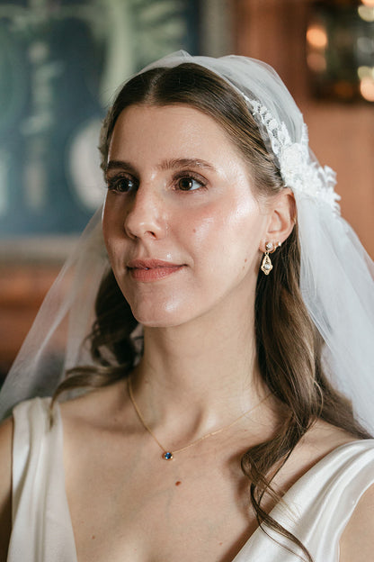 A bride wearing a dainty blue gold necklace and a Juliet cap veil with applique and loose downdo from one blushing bride
