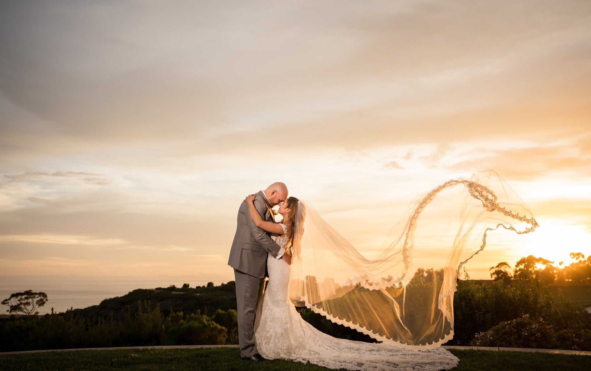 Load video: real brides wearing long cathedral veils with drop blusher and lace edge at Pelican Hill in Newport Beach