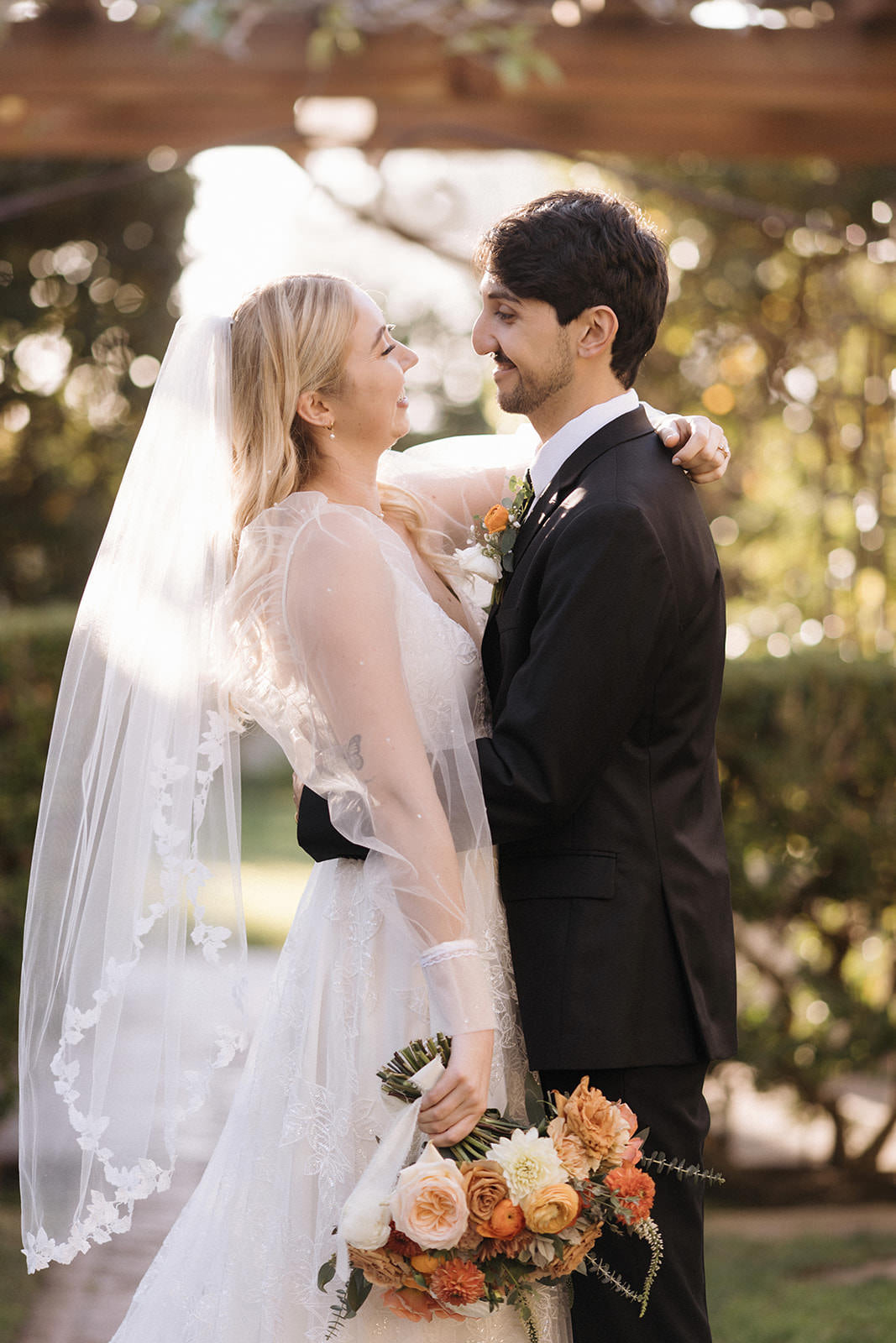 bride and groom embracing with bride in whimsical organic vine bridal veil and puffy sheer wedding sleeves