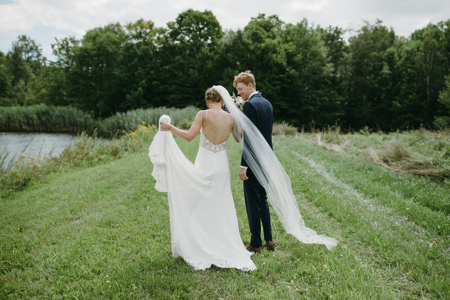thin and narrow minimalist bridal gown in off white for wedding in a meadow