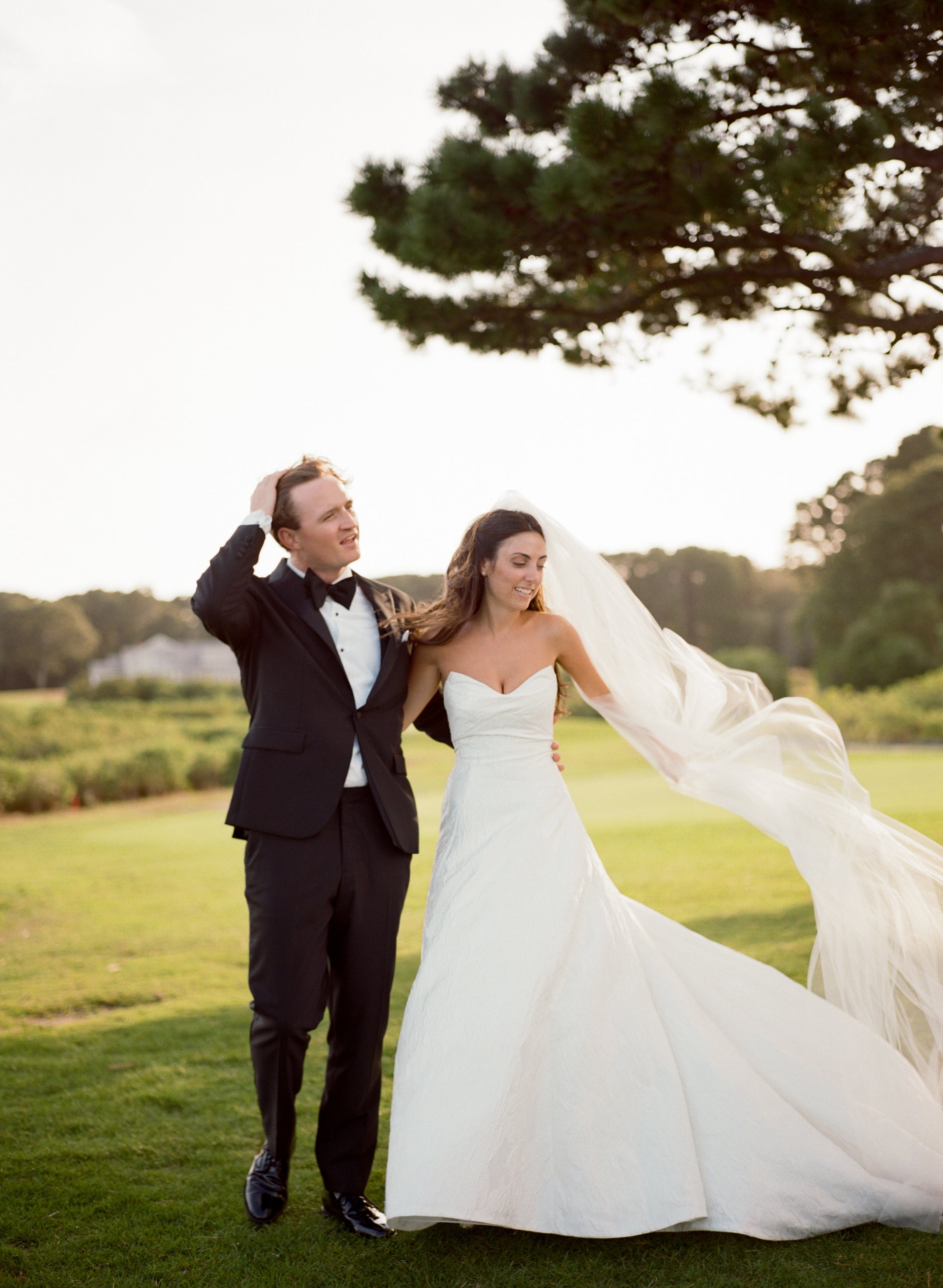 Wedding couple standing on a grassy field with bride in light ivory cathedral length bridal veil from soft bridal illusion tulle