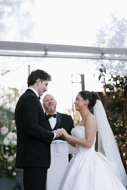 Wedding ceremony with a couple holding hands in front of an officiant and bride in bun updo with simple raw edge under the hair