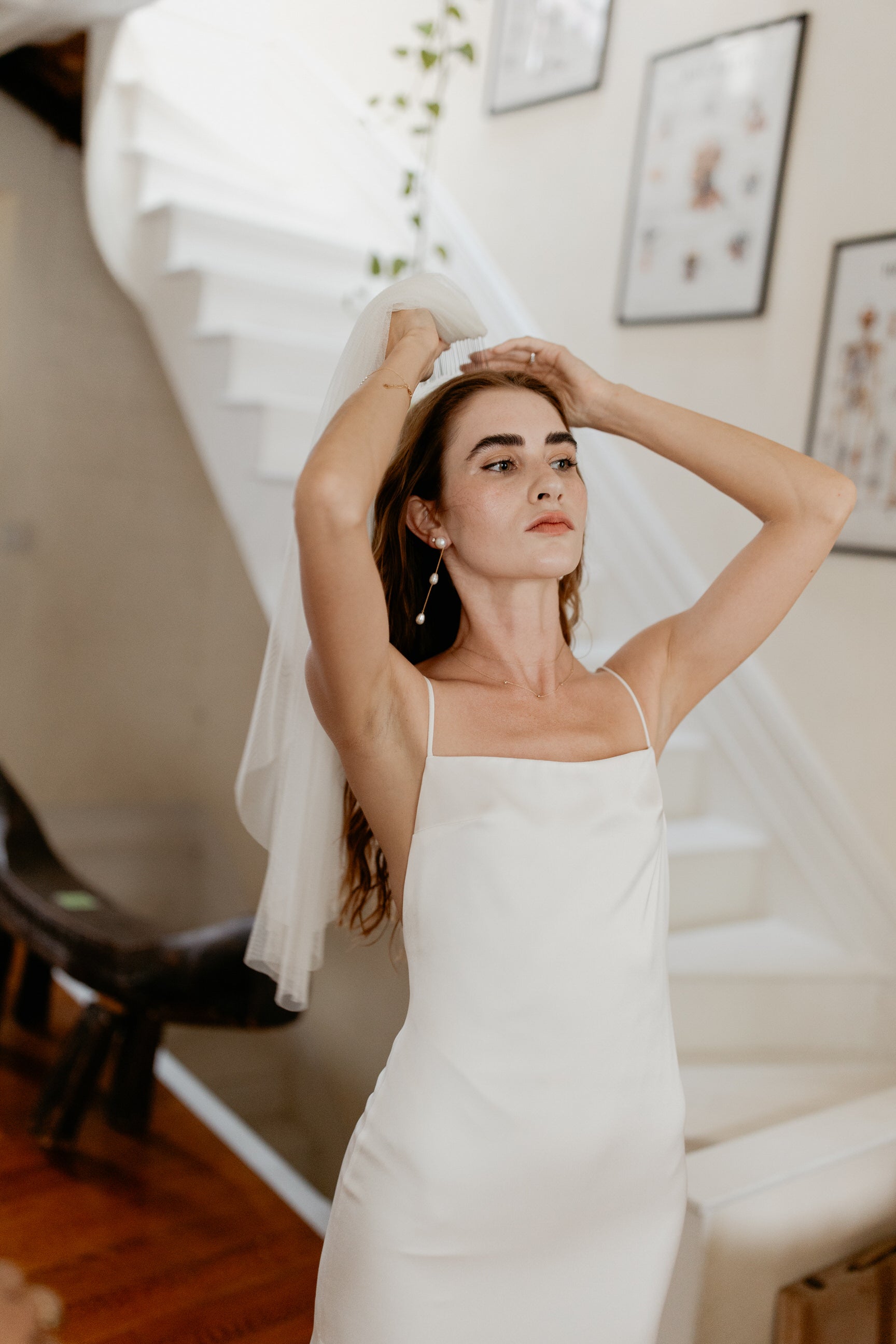 minimalist bride putting on simple cut edge waist length bridal veil