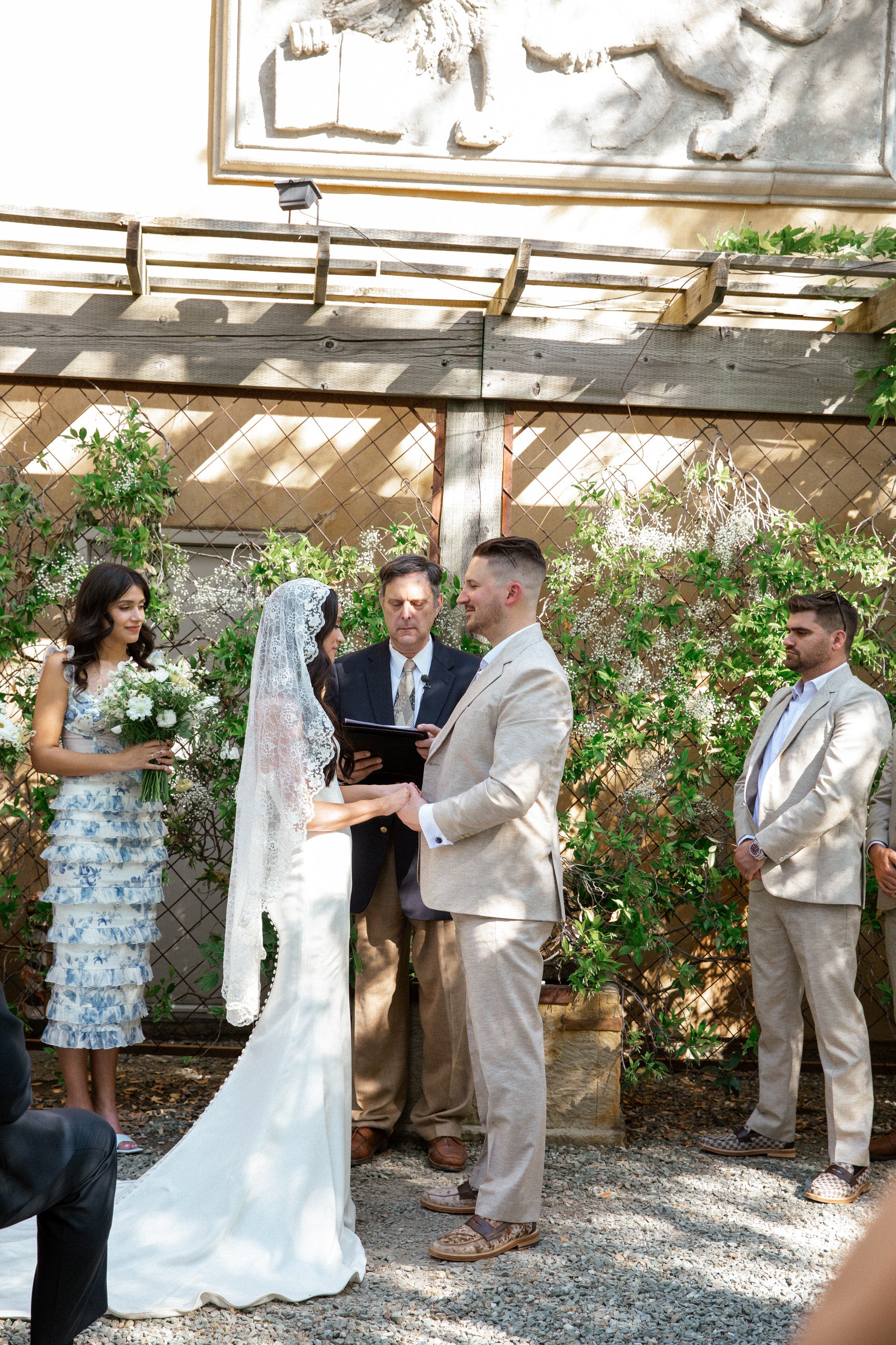 romantic outdoor ceremony with bride wearing ivory French lace mantilla wedding veil and a buttoned long white dress