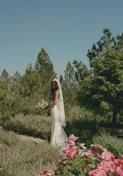 botanical wedding with bride wearing a fingertip length all lace mantilla veil from one blushing bride and holding dainty wildflowers