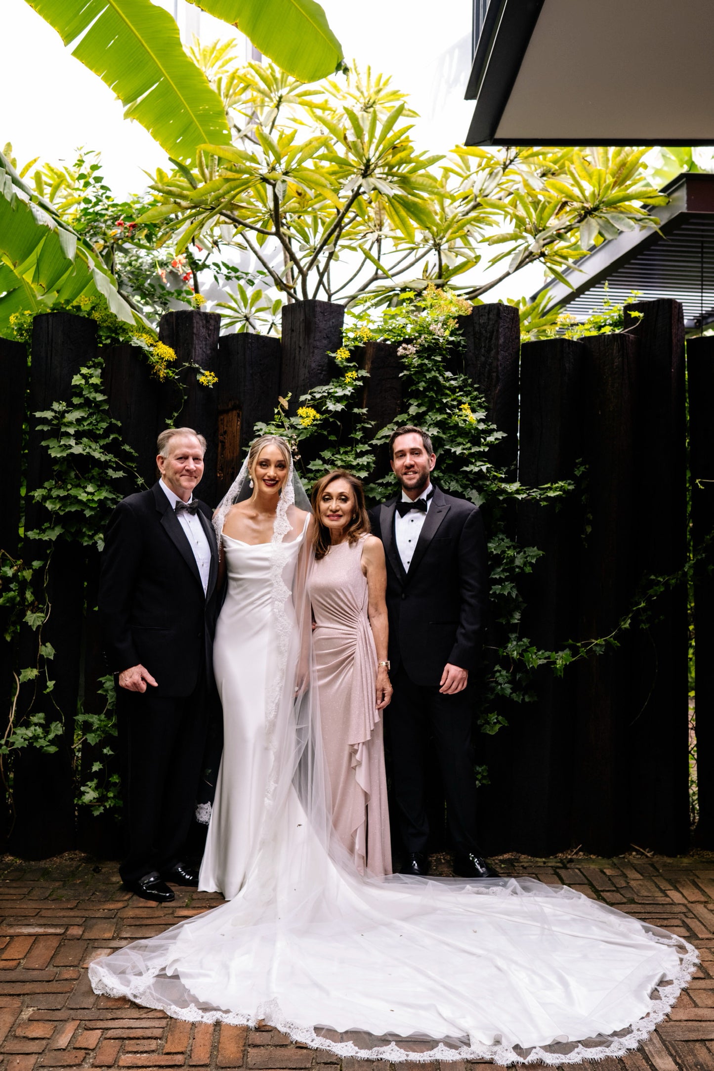 family portrait of lace edged eyelash mantilla long bridal veil in Mexican hacienda patio with palm trees