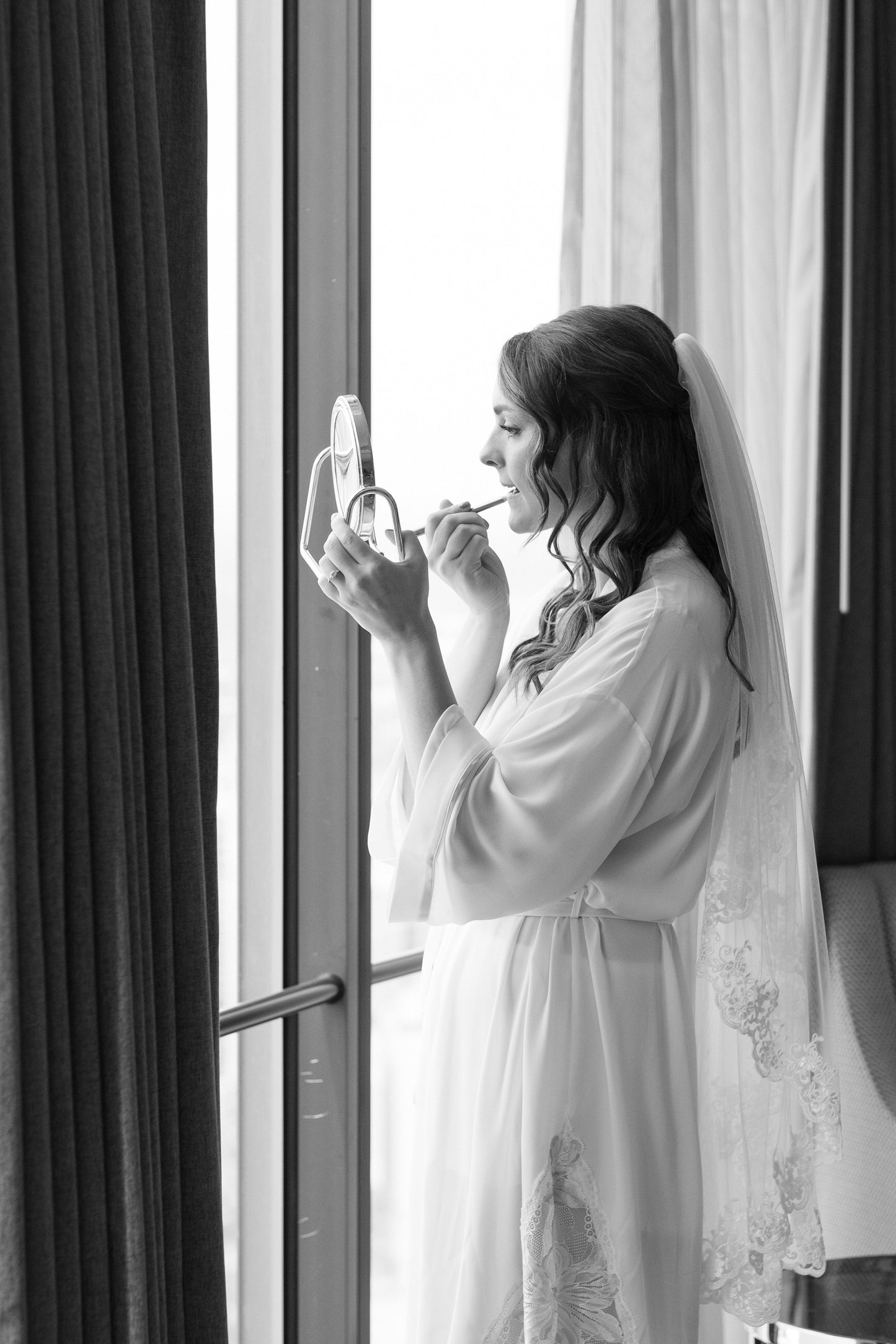 bride in fingertip length cascade lace wedding veil putting on makeup