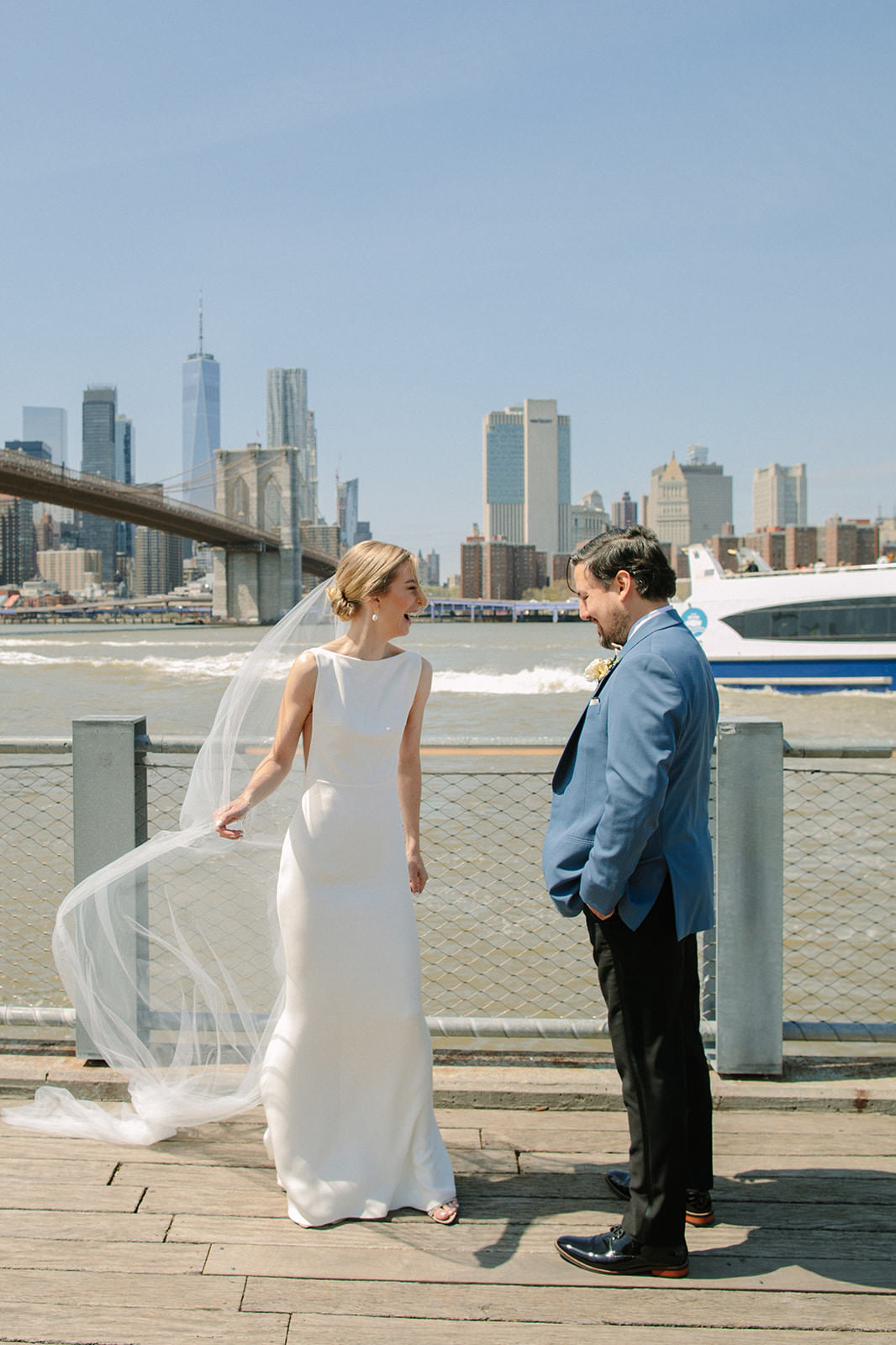 Brooklyn first look with silk off white cathedral length wedding veil blowing in the harbor wind