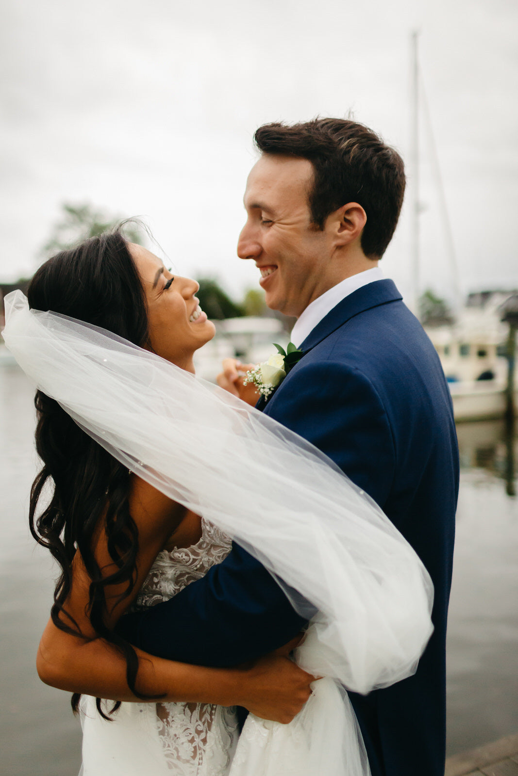 bride in long white beaded veil and groom in navy suit