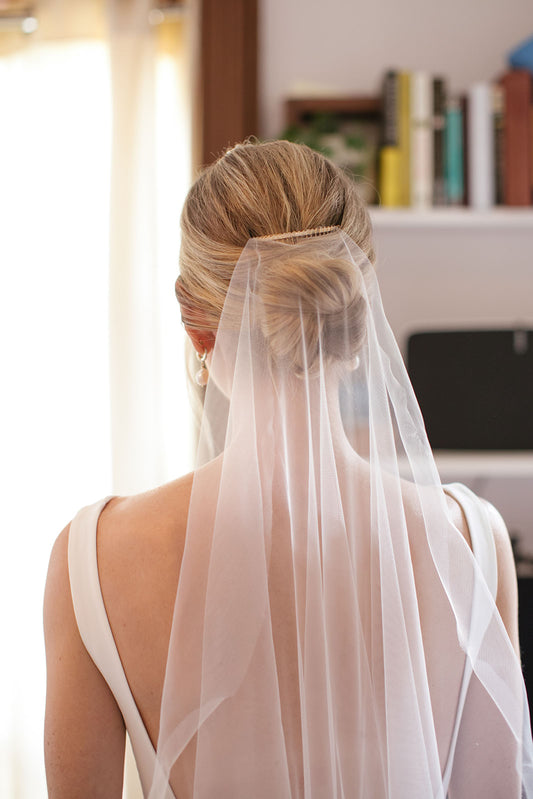 barely there silk bridal veil attached to gold comb in bride's low updo knot