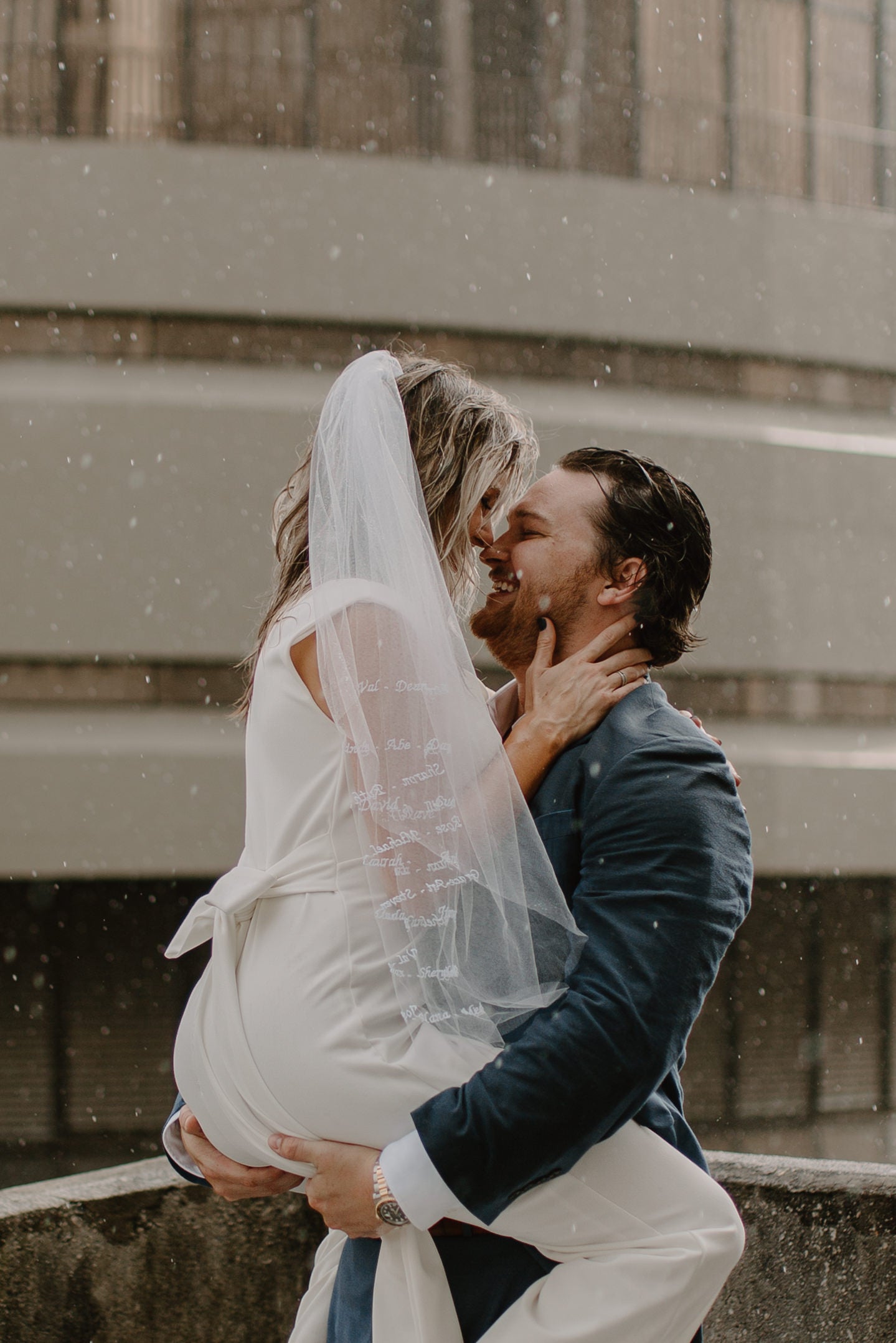 simple mid length bridal veil with bespoke script writing as couple embraces in the rain