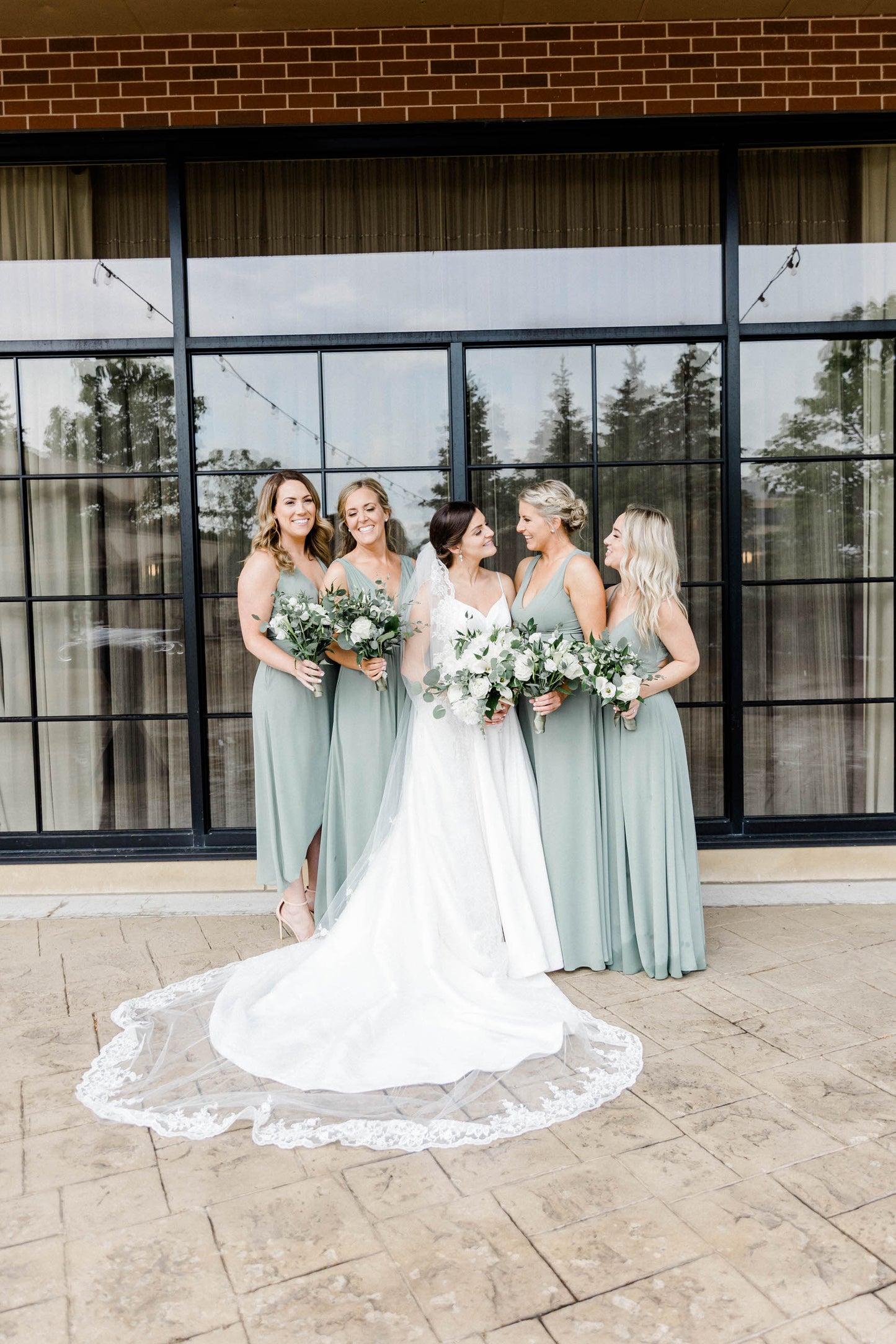 long white bridal veil with wide lace trim edge and bridesmaids in mint sage dresses