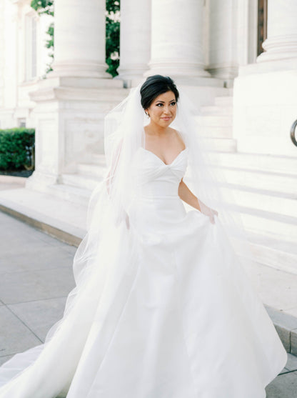 classic traditional bride in long puffy cathedral length bridal veil with cut edge and holding her ballgown 