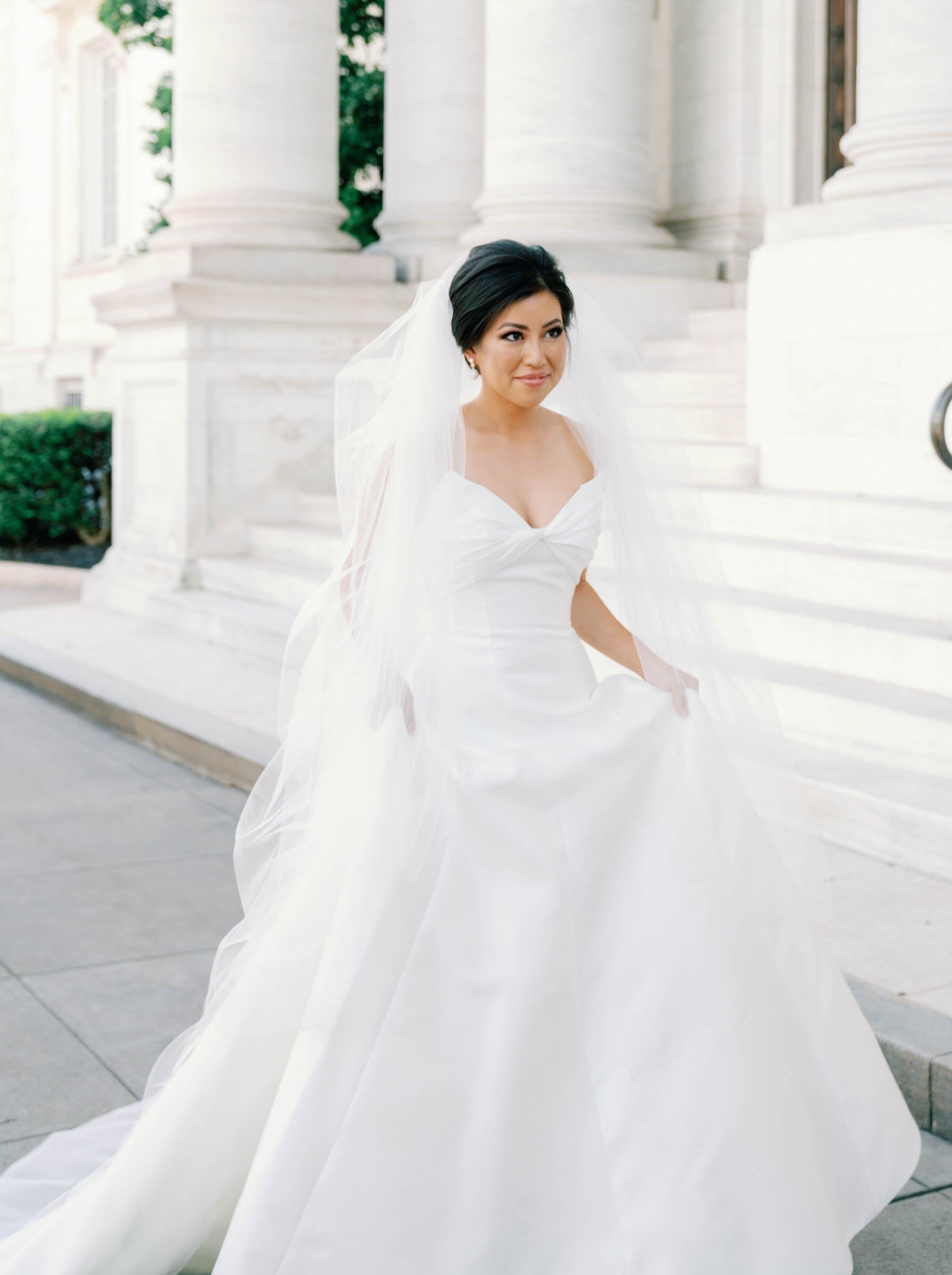 classic traditional bride in long puffy cathedral length bridal veil with cut edge and holding her ballgown 