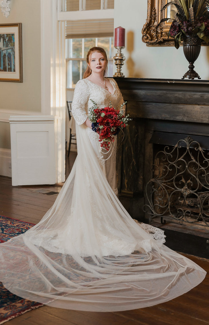 glamorous ivory bridal cape with red bouquet with pearls