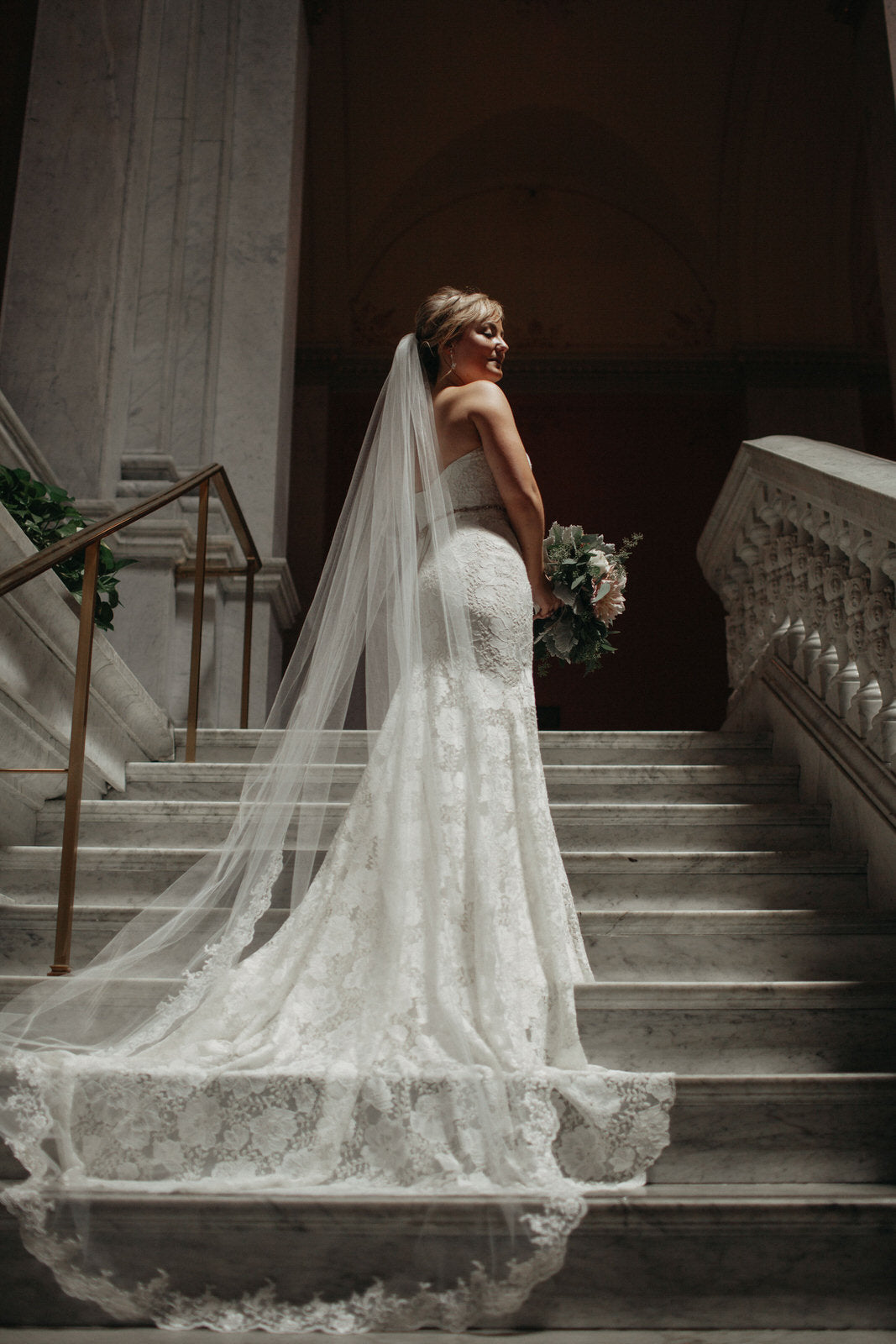 bride on staircase in light ivory cathedral wedding veil with trim