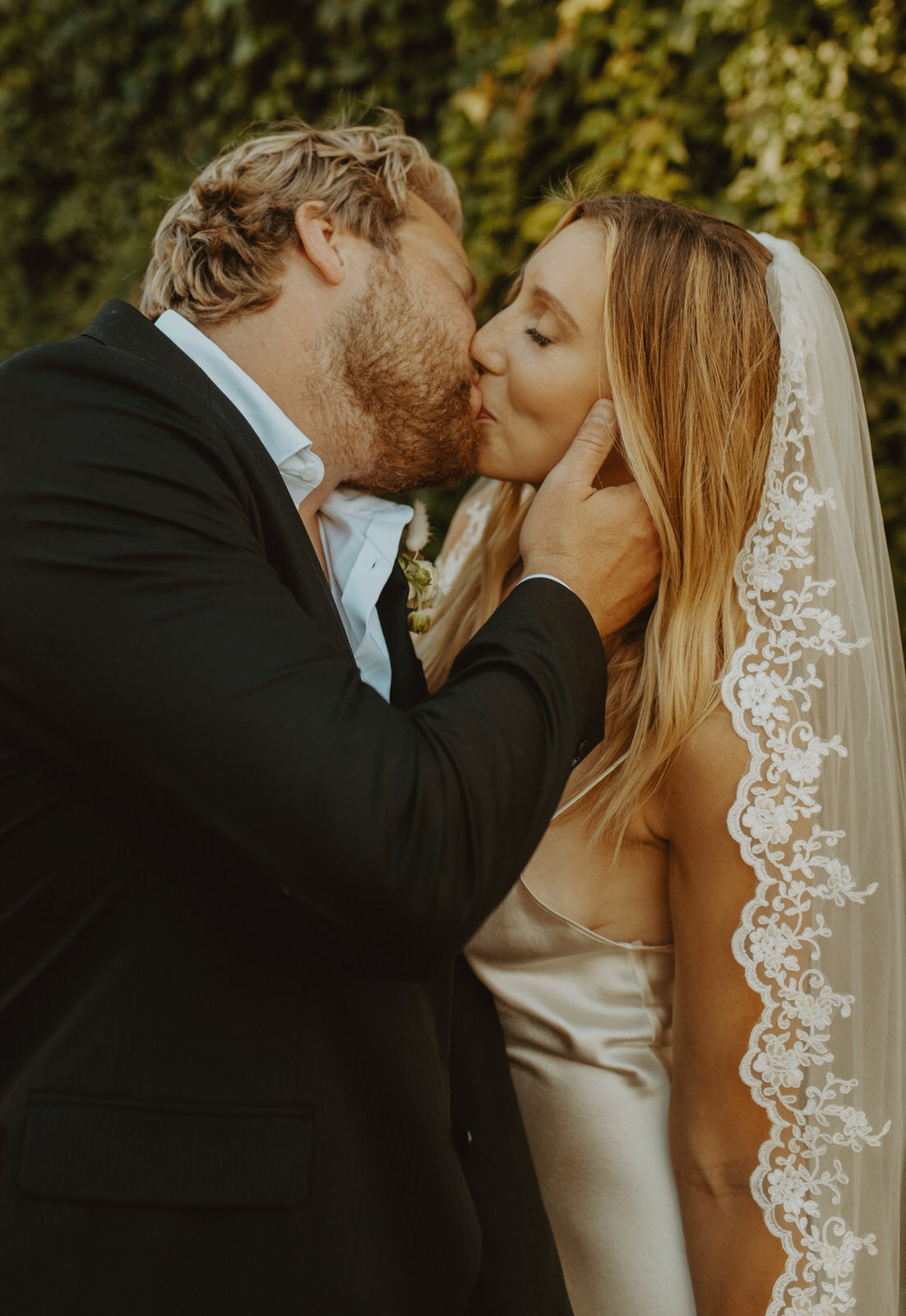 couple kissing with bride in floral lace trim bridal veil
