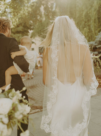 minimalist bride in low back dress and one layer mantilla lace wedding veil as she walks into the sun