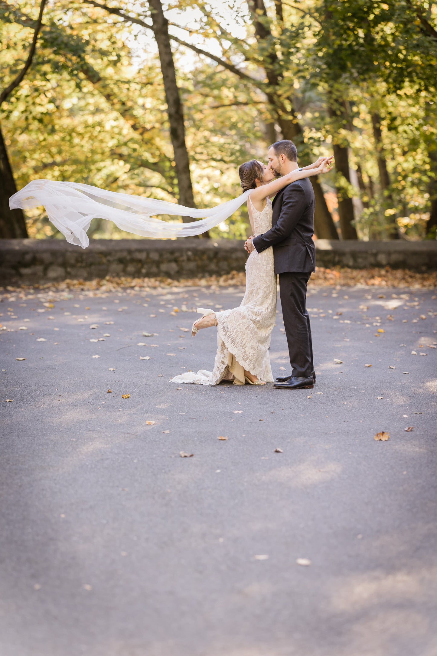 embracing groom with long cathedral length bridal wings blowing in wind