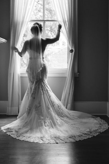 bride in one tier veil looking out window