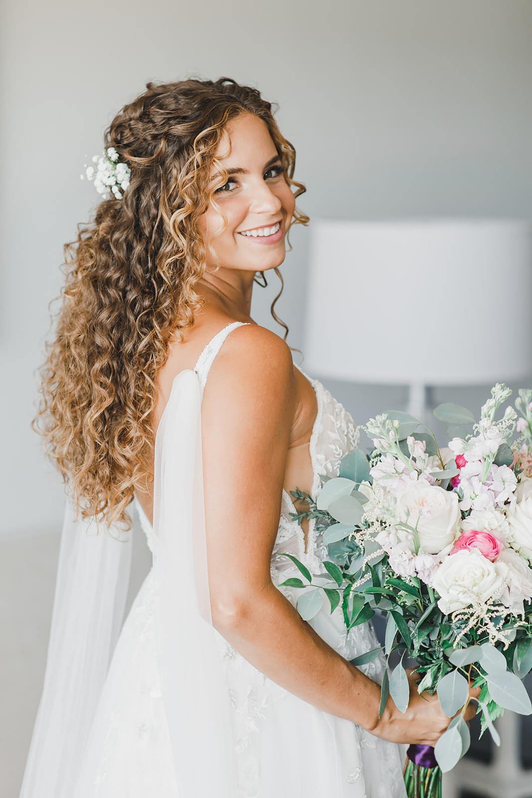 silk bridal wings pinned at shoulders on bride with natural and romantic curly hair with baby's breath flowers
