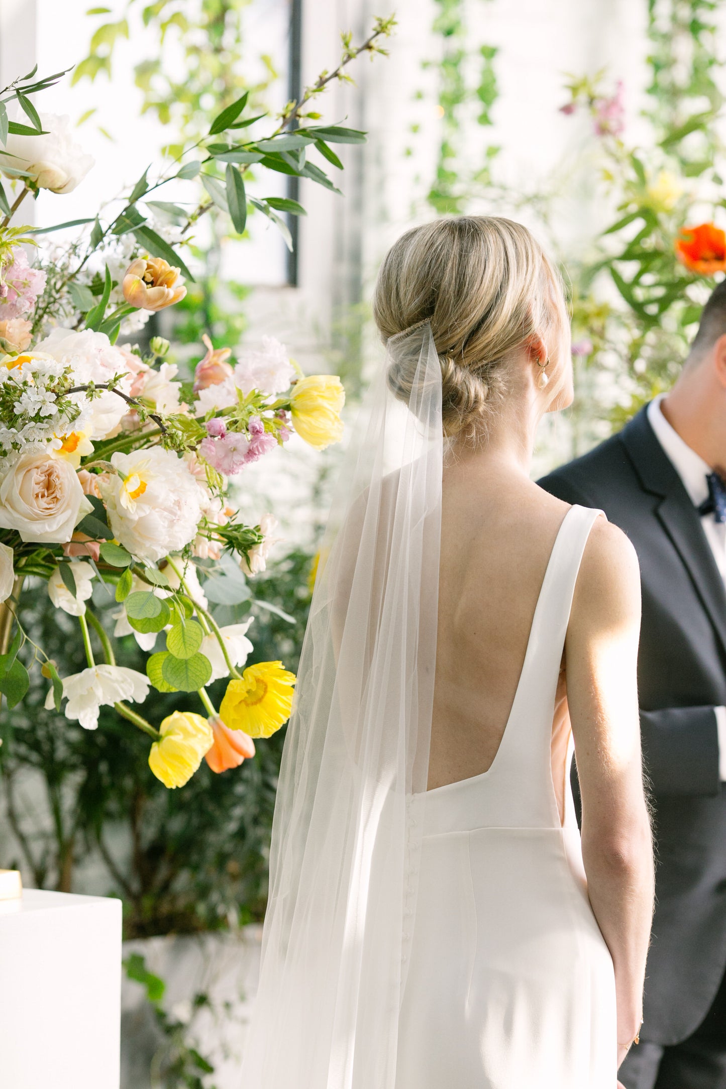 garden inspired wedding with bride tilting head with barely there cascade wedding veil over low bun