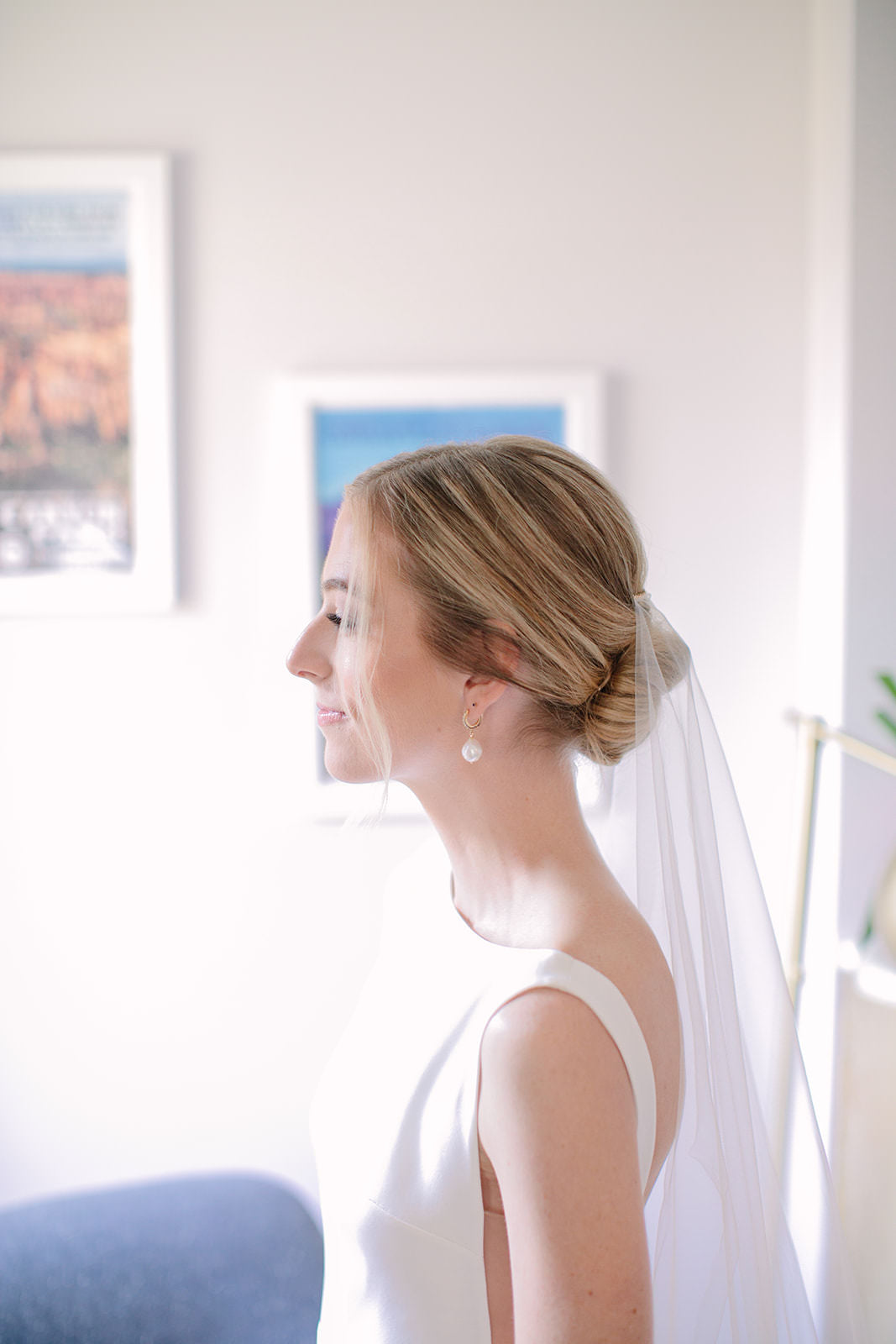 minimalist and elegant bride with soft cascade circle cut wedding veil over her low bun and pearl earrings